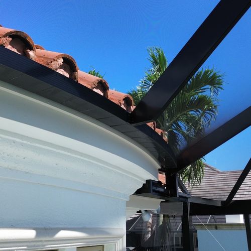 Close-up of aluminum frame connection to tile roof for a screen enclosure in Naples, FL, showcasing expert installation detail.
